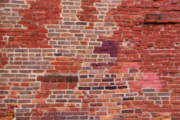 Horizontal view of old wall with patches of different coloured bricks in irregular pattern