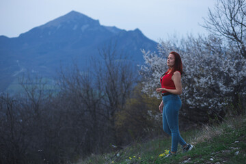 Curvy young woman posing in the dusk mountains. A peaceful evening. Relax, loneliness