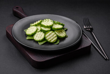 Delicious healthy raw cucumber sliced ??on a black ceramic plate