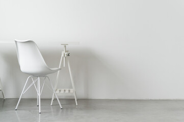 A white table and a chair near a white wall