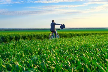 Fototapete Rund Grün a businessman rides a bicycle with a briefcase on a green grassy field, dressed in a business suit, beautiful nature in spring, freelance business concept  © soleg