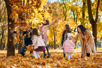 portrait of a large family with children in an autumn city park, happy people playing together and throwing yellow leaves, beautiful nature, bright sunny day