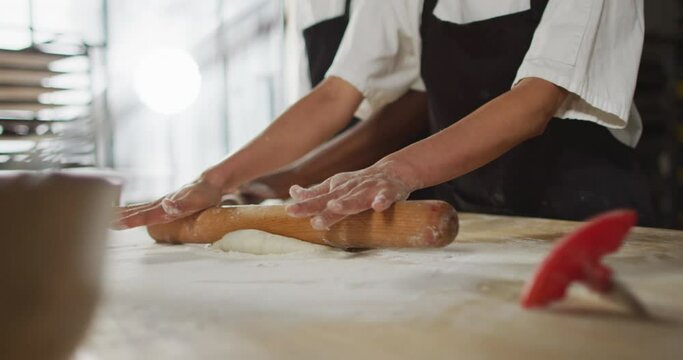 Animation of hands of asian female baker rolling sourdough for bread