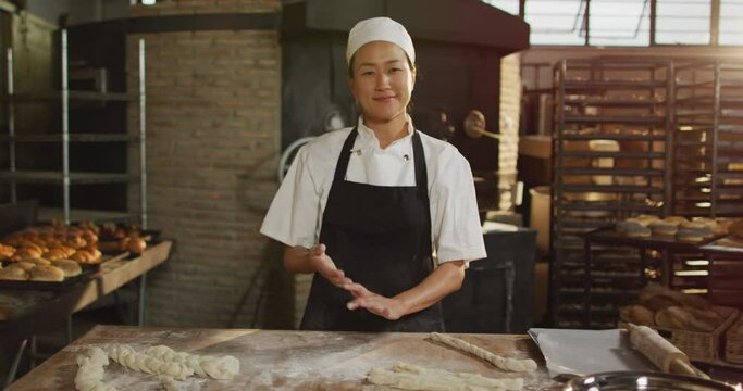 Animation of happy asian female baker cleaning hands from four and smiling at camera