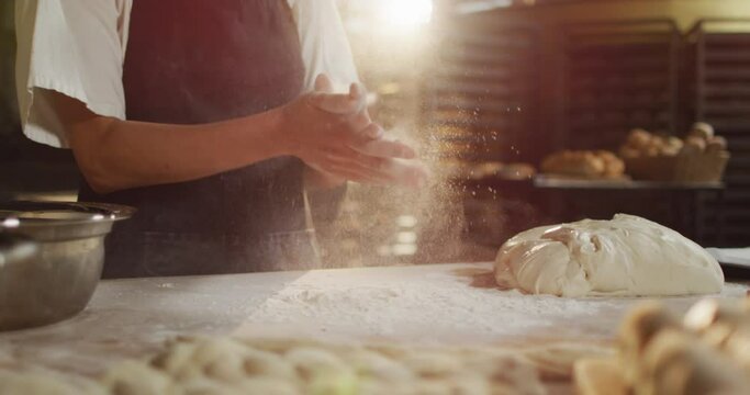 Animation of midsection of biracial male baker clapping hands to clean flour at bakery