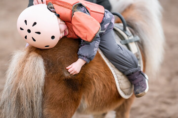Little Child Riding Lesson. Three-year-old girl rides a pony and does exercises