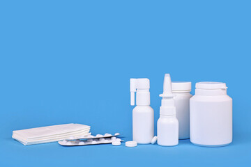 Various medication for cold and flue. Nasal spray, throat spray, pills and tissues on blue background with copy space