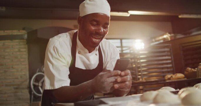 Animation of happy african american male baker using smartphone