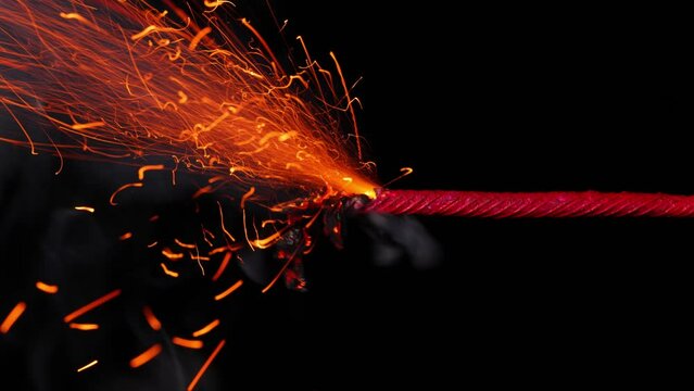 A macro shot of a burning fuse in front of a black background.