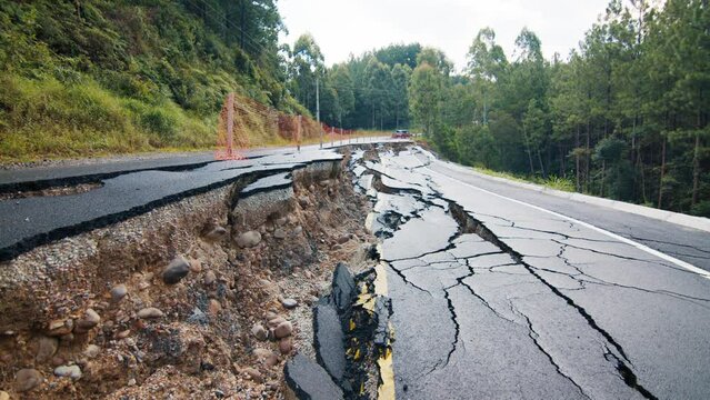 Damaged asphalt road in the mountains. Mudflow aftermath, cracked paved road