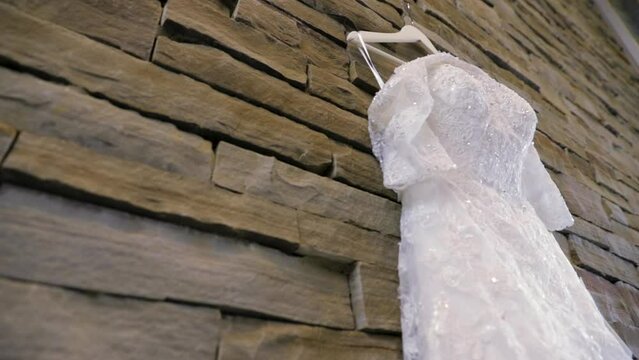 Wedding Dress Hangs Against Wall