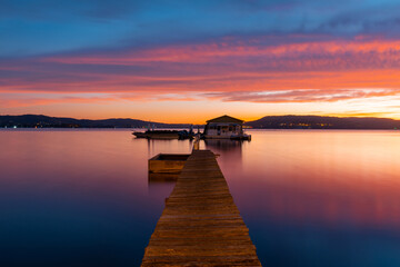 Jetty and small hut with colorful dawn sky.