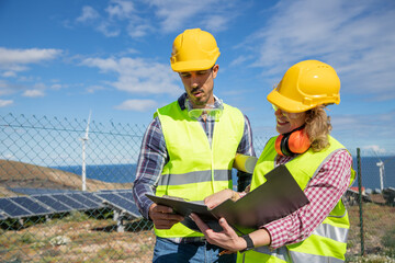 Two engineers at work analyze data in the solar farm, female and male coworkers
