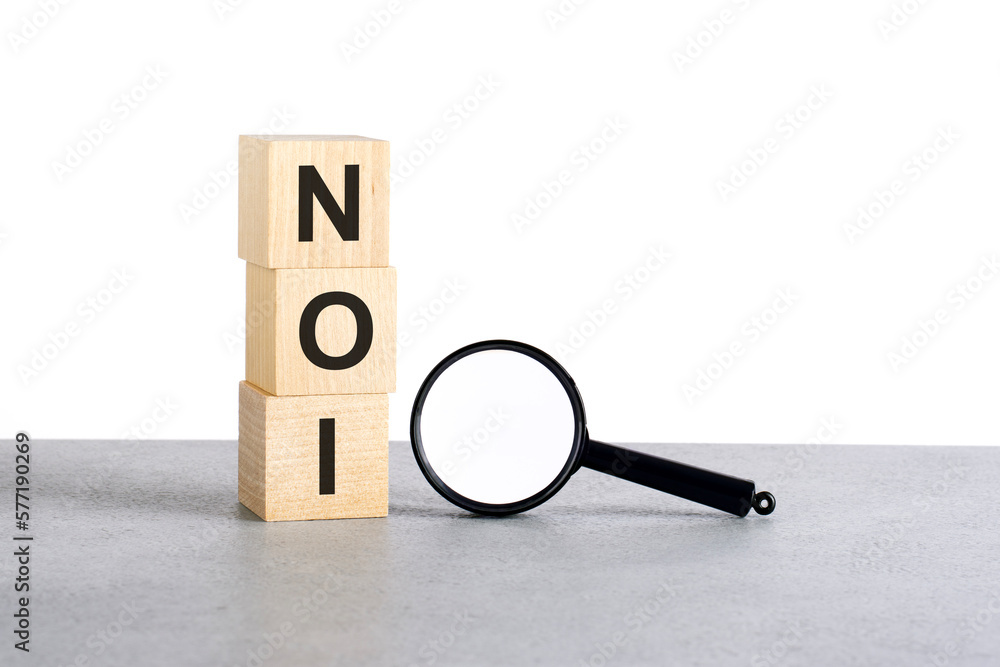 Poster noi - net operating income - text wooden cube blocks and magnifying glass on grey table