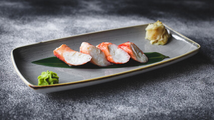 Crab meat on a leaf in a stylish plate on a dark background. Asian food.