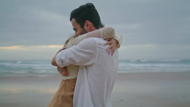 Engaged couple embracing at ocean sunset beach closeup. Boyfriend swirling bride