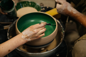 Pottery master class people hands make a clay deep bowl and paint it green with brush