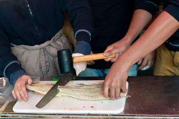 Cutting dried bacala in fish market of Bergen, Norway