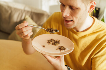 Man holds spoonful of cooked insects - a sustainable, protein-rich food source for the future....