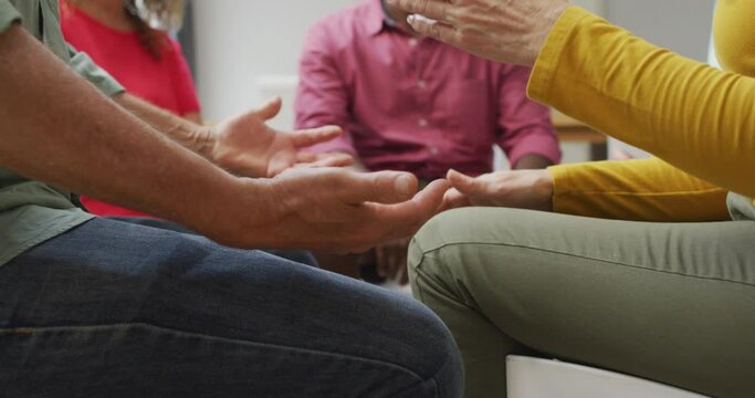 Animation of midsection of diverse seniors holding hands during support group meeting