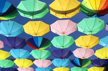 unos paraguas de colores colgados con un cielo azul