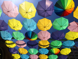 unos paraguas de colores colgados con un cielo azul