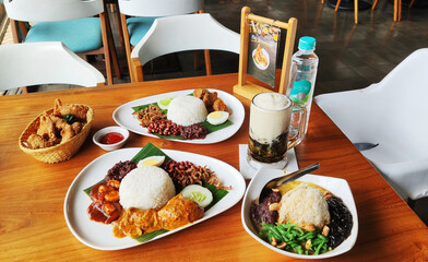 A Malaysian cuisine Nasi Lemak coupled with fried chicken skin served at the table alongside Es Cendol and Es Kacang.
