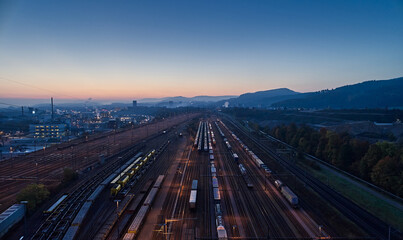 Fototapeta na wymiar Güterbahnhof mit Wagons auf Abstellgleisen im Industrieviertel. Morgendämmerung, blaue Stunde und Morgenrot am Horizont.