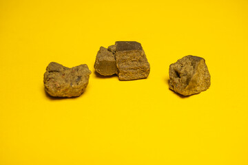 Pieces of high quality dry sift hashish isolated on a yellow background. Medical marijuana extraction hash cannabis pollen hashish