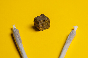 Medical Cannabis Hashish Marijuana rolled Joints with a piece of hash isolated on a yellow background.  Cool flat lay, copy space