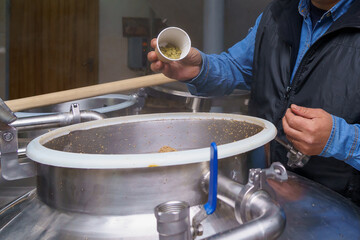 The process of adding malt to a vat at a brewery, motion blur, steam from brewing beer. Background