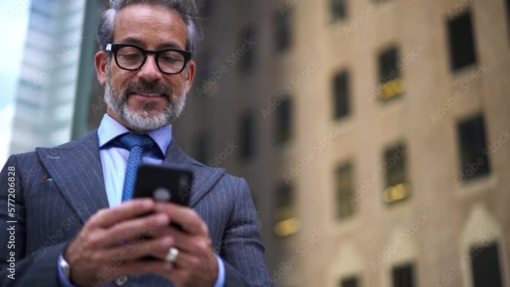 Poster bottom view, smiling male with gray hair holding cellular phone in hands and typing text message whi