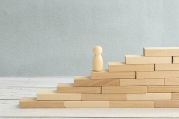 wooden figure - man climbing the steps to success in image over white background