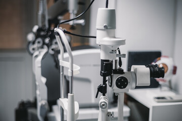 A doctor's ophthalmology office, with a white photo-coagulation laser machine in focus and surroundings, creates a sterile, clinical environment in the foreground
