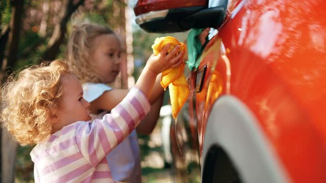 Little girls wash red car together