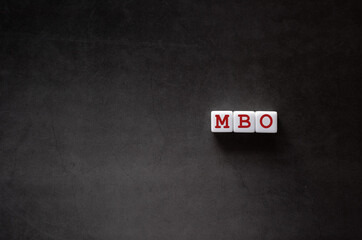 There is white cube with the word MBO. It is an abbreviation for Management by Objectives as...