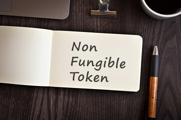 There is notebook with the word Non-Fungible Token. It is an eye-catching image.