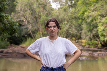 Mujer joven mirando a la cámara, enojada, en medio de la naturaleza.