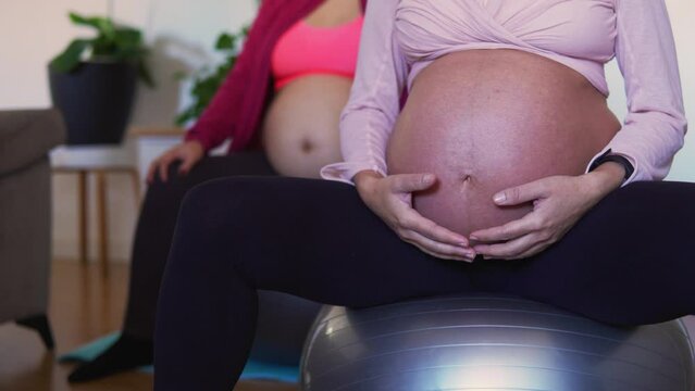 Unrecognizable pregnant women getting ready for pilates exercises with ball