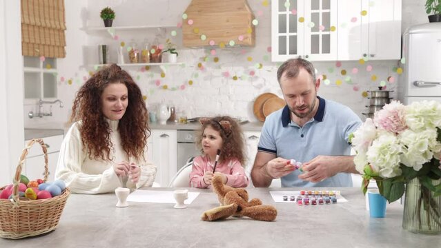 Portrait of cute family spending time together with their daughter. Caucasian parents playing with their cute daughter in home kitchen with beautiful decorations. High quality 4k footage