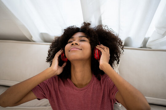 Rest And Relax Concept. Calm Black Woman Sitting On Sofa, Listening To Music, Streaming, Podcast, Enjoying Meditation For Sleep And Peaceful Mind In Wireless Headphones, Leaning Back, Copy Space