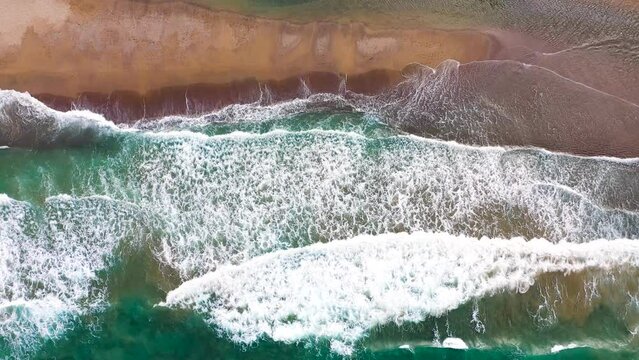 Aerial view of the Mediterranean coast, waves reach the deserted sandy beach