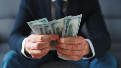 Formally dressed man counting US Dollar bills, close-up.