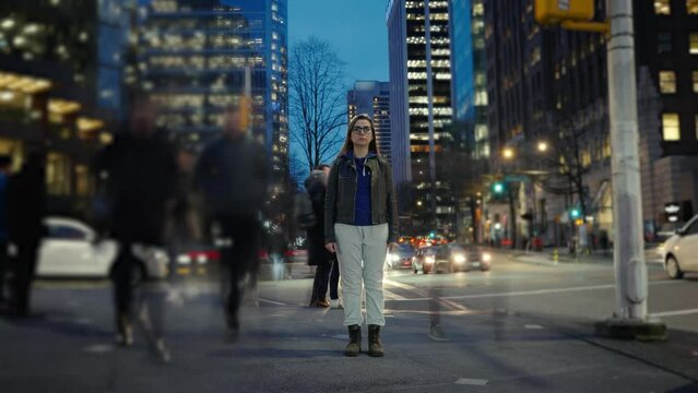 Time-lapse of woman standing still on crowded evening street