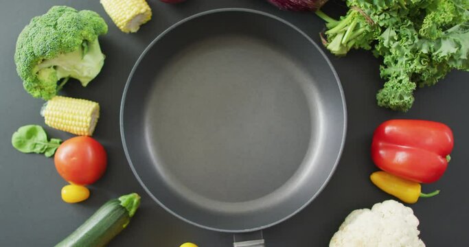 Video of fresh vegetables around frying pan with copy space on grey background