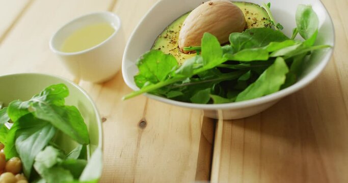 Video of bowls of fresh salad with green leaves on wooden background
