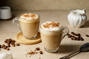 Two glass cups with coffee drink, latte with milk foam and cinnamon