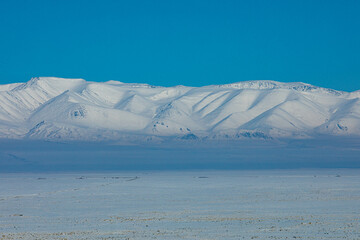 View from Chui steppe to South Chui ridge in winter day. Russia South Of Western Siberia, Altai Mountains. Desert mountains covered with snow near village of Kosh-Agach