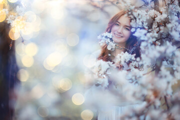 spring portrait of an adult happy woman in a blooming garden, sun rays and glare, april flowers girl