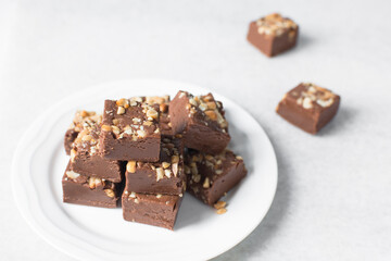 chocolate fudge with nuts on a marble tray, chocolate fudge cut into pieces, fudge candy on a marble tray